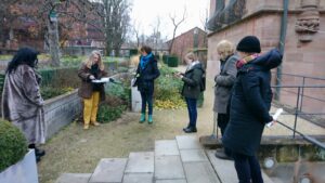 Gruppe von sechs Personen steht in halbrundem Bogen im Garten des Tucherschlosses in Nürnberg zur Besprechung