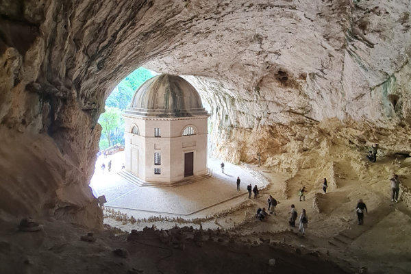 Blick aus einer Höhle auf einen kleinen Rundtempfel am Höhlenausgang