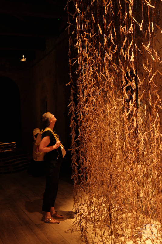 Anja Zimmermann steht mit nach oben gerichtetem Blick vor der vorhangartigen Installation
