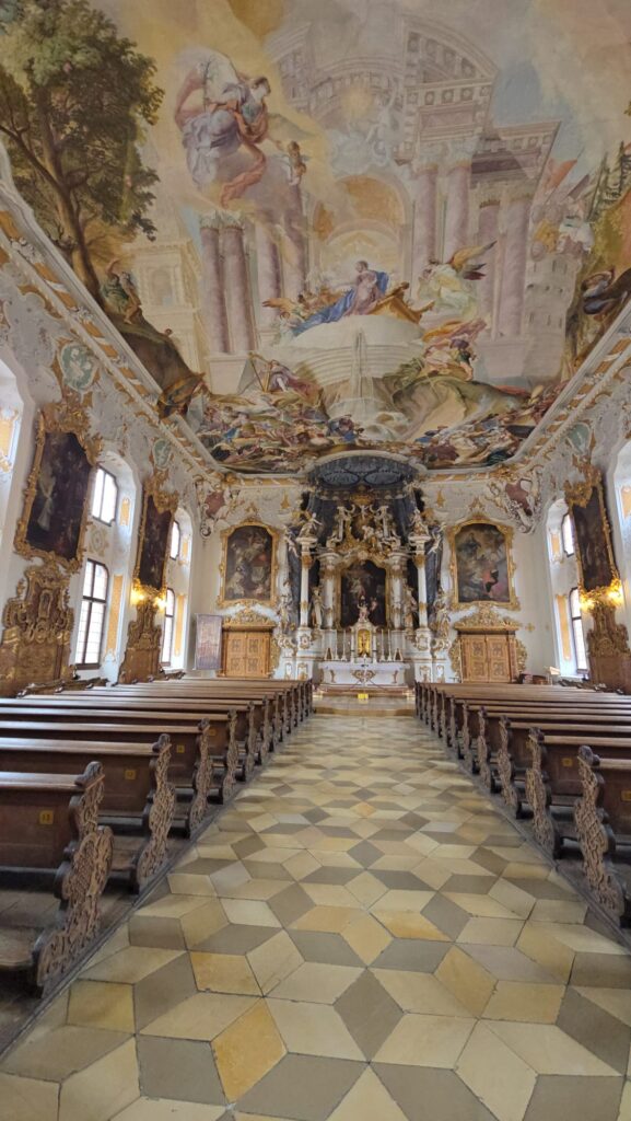 Heller Kirchenraum mit Blick auf den Hochaltar und beeindruckendem Deckenfresko
